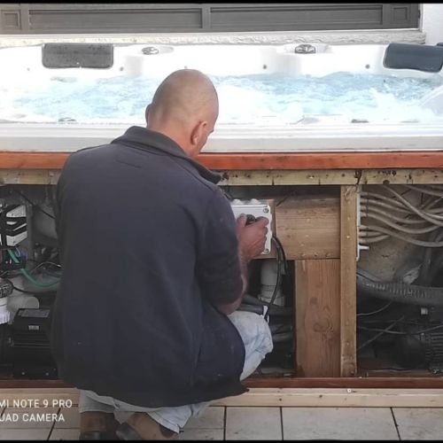 טכנאי מטפל ברכיבי מערכת ג׳קוזי מאחורי דופן פתוחה