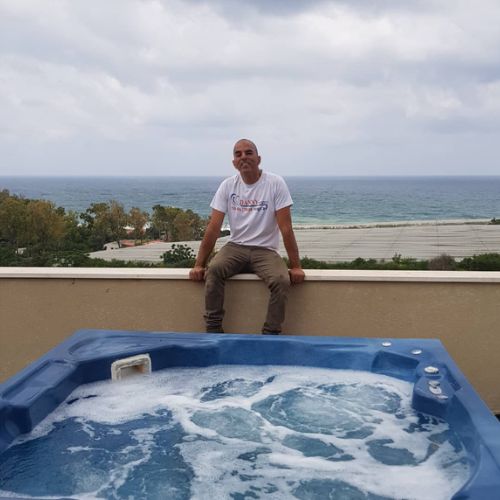 טכנאי דני ג'קוזי ליד ג'קוזי פעיל עם נוף ים, שירות תיקון ושדרוג.