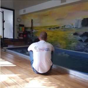 טכנאי דני ג'קוזי בודק ג'קוזי בחדר עם ציור ים, שירות תיקון ושדרוג מקצועי.